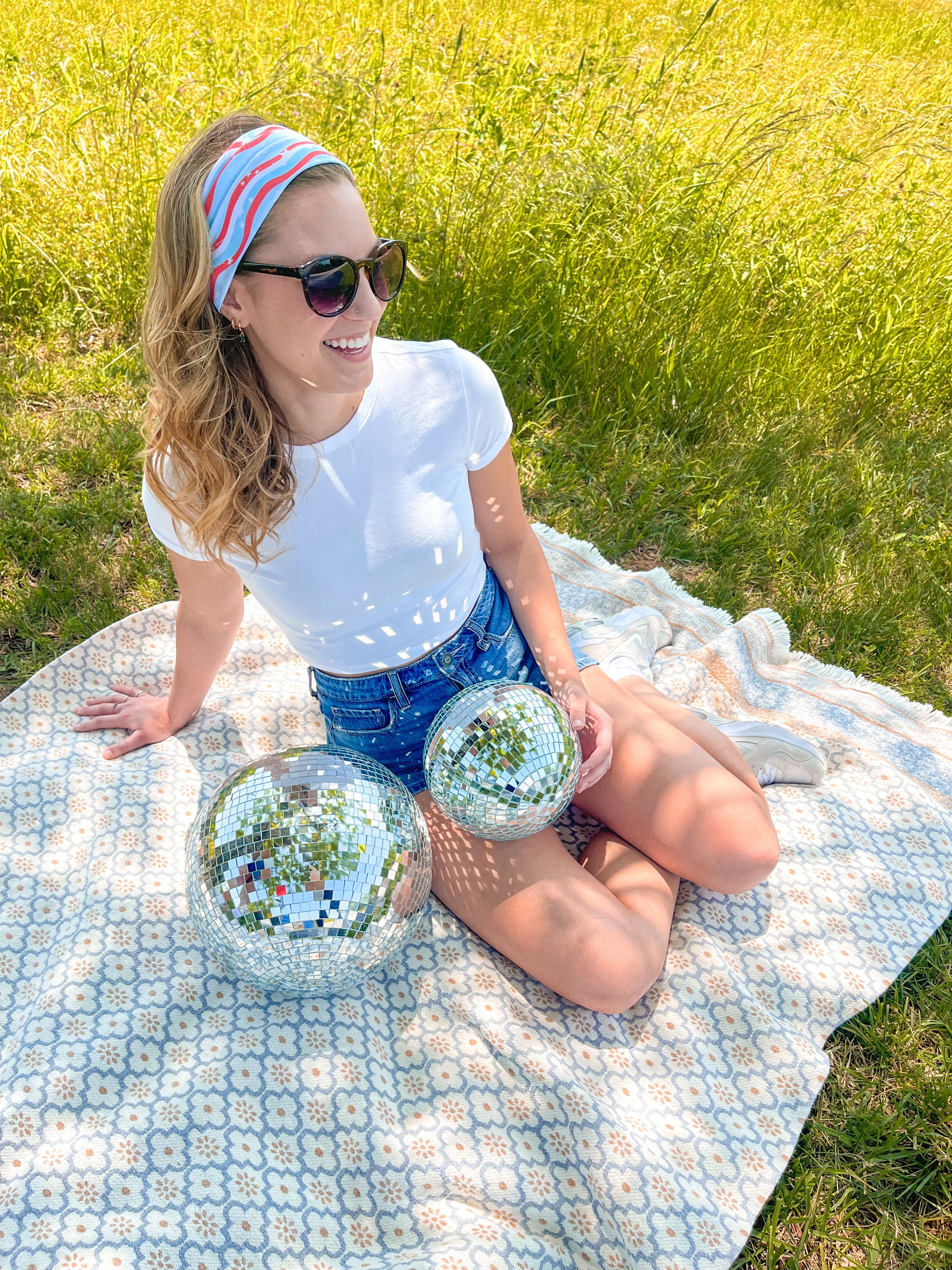 A woman confidently wears a Courtesy of Red, White and Blue headband outdoors, featuring a versatile 3-in-1 twist style for various looks. Designed for comfort and functionality, perfect for workouts or long shifts.