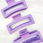 A group of purple Vacation Vibes Lilac Clips, 4.8 inches long, matte material, with a hinge closure. Perfect for all hair types, keeping hair out of your face.