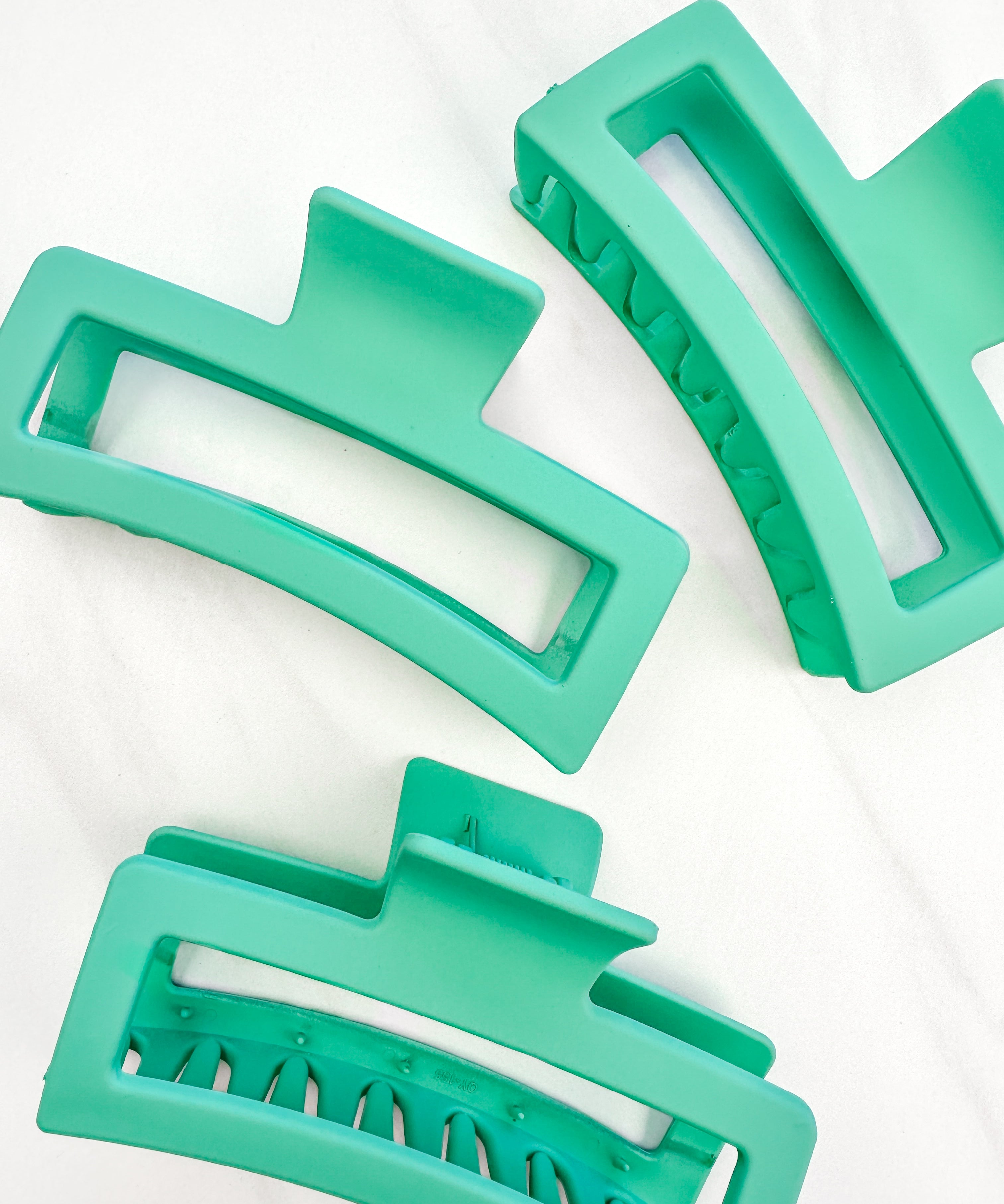 A group of green Vacation Vibes Lilac Clips, 4.8 inches long, matte material, with a hinge closure. Perfect for all hair types, keeping hair out of your face.