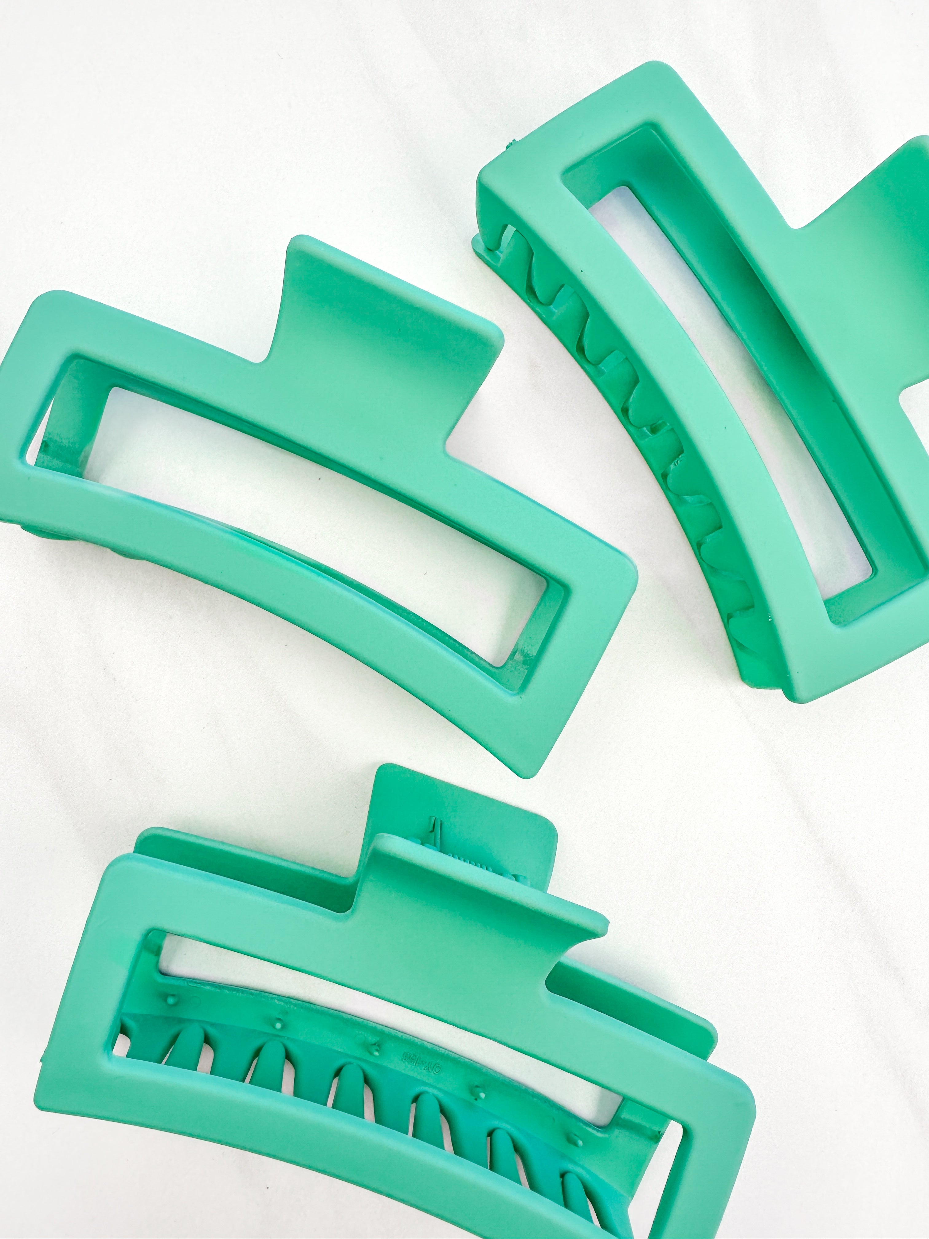 A group of green Vacation Vibes Lilac Clips, 4.8 inches long, matte material, with a hinge closure. Perfect for all hair types, keeping hair out of your face.