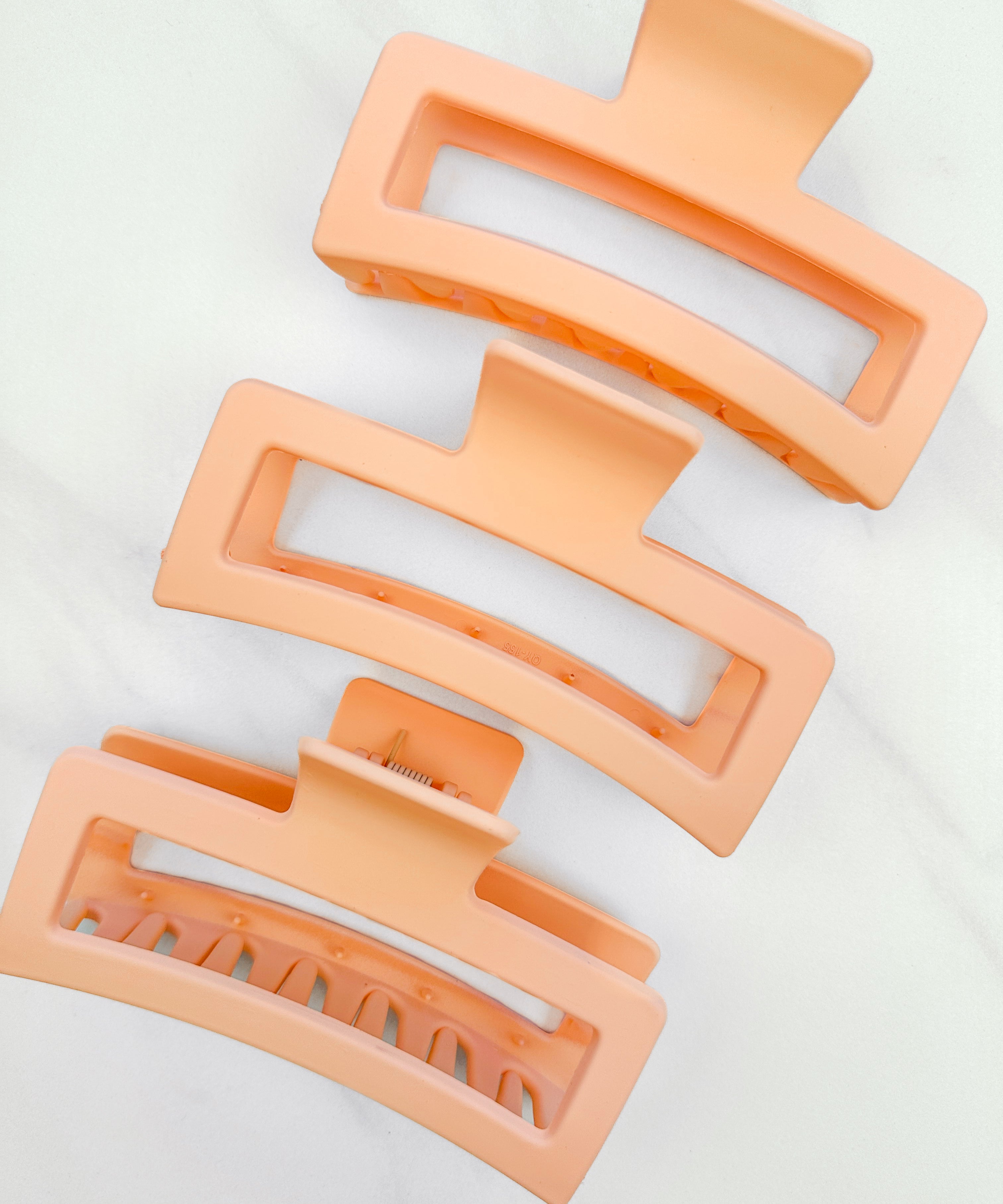 A group of orange Vacation Vibes Lilac Clips, 4.8 inches long, matte material, with a hinge closure. Perfect for all hair types, keeping hair out of your face.