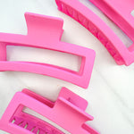 A group of pink Vacation Vibes Lilac Clips, 4.8 inches long, matte material, with a hinge closure. Perfect for all hair types, keeping hair out of your face.