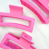 A group of pink Vacation Vibes Lilac Clips, 4.8 inches long, matte material, with a hinge closure. Perfect for all hair types, keeping hair out of your face.