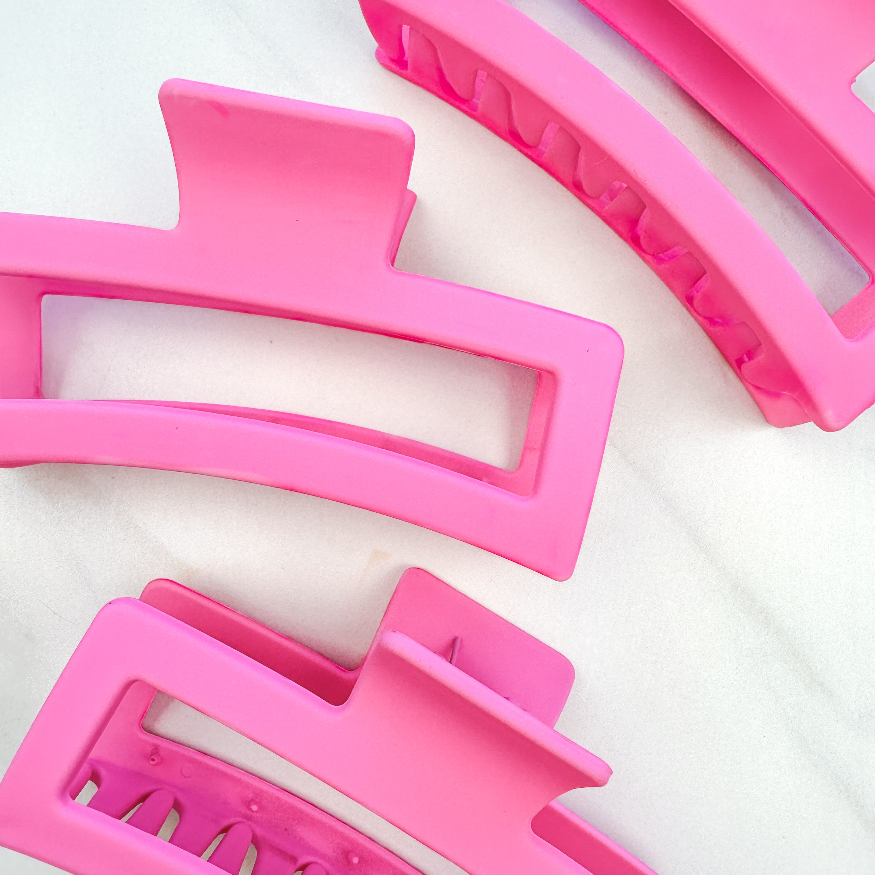 A group of pink Vacation Vibes Lilac Clips, 4.8 inches long, matte material, with a hinge closure. Perfect for all hair types, keeping hair out of your face.