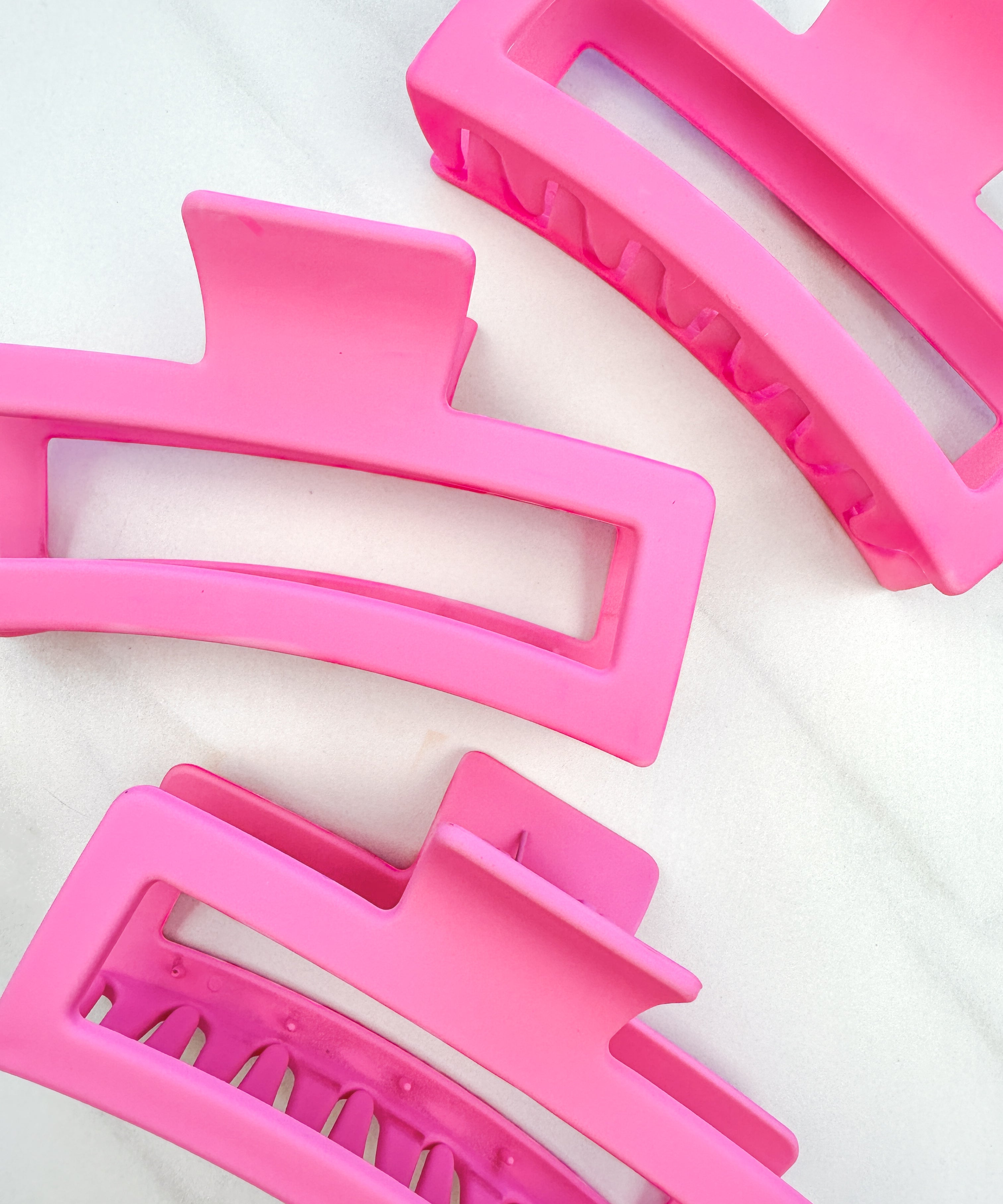 A group of pink Vacation Vibes Lilac Clips, 4.8 inches long, matte material, with a hinge closure. Perfect for all hair types, keeping hair out of your face.