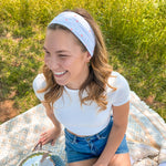A woman confidently wears the Oh My Stars headband, showcasing its versatile twist style and sweat-absorbent fabric. Designed for function and style, perfect for workouts or play days.