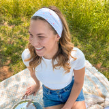 A woman confidently wears the Oh My Stars headband, showcasing its versatile twist style and sweat-absorbent fabric. Designed for function and style, perfect for workouts or play days.