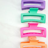 A group of various colors of Vacation Vibes Lilac Clips, 4.8 inches long, matte material, with a hinge closure. Perfect for all hair types, keeping hair out of your face.