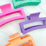 A group of various colors of Vacation Vibes Lilac Clips, 4.8 inches long, matte material, with a hinge closure. Perfect for all hair types, keeping hair out of your face.