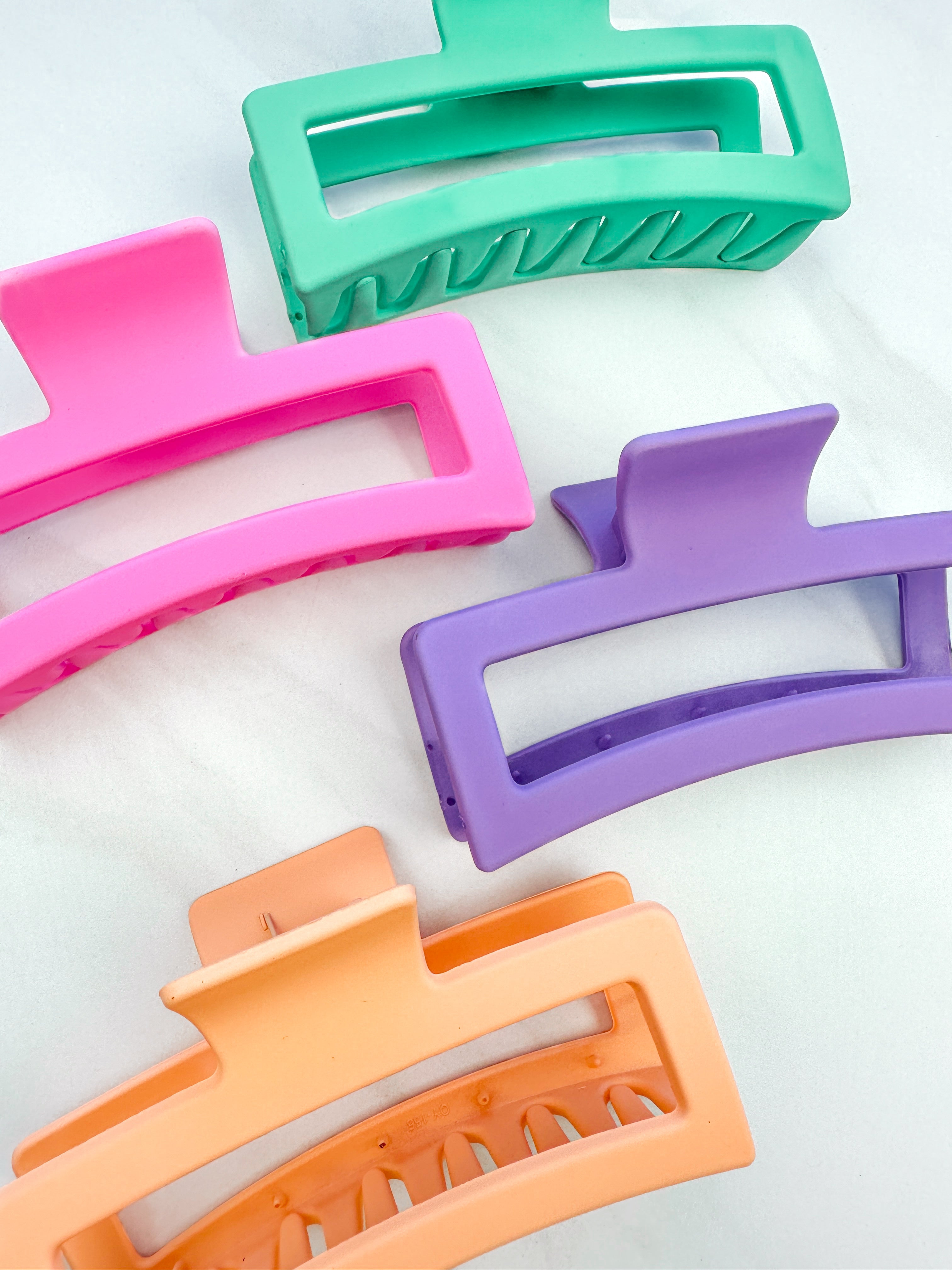 A group of various colors of Vacation Vibes Lilac Clips, 4.8 inches long, matte material, with a hinge closure. Perfect for all hair types, keeping hair out of your face.