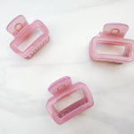 A close-up of a pink Happy Hour Lilac Clip, a glossy hair accessory with a hinge closure, perfect for all hair types. 1.8 inches long.