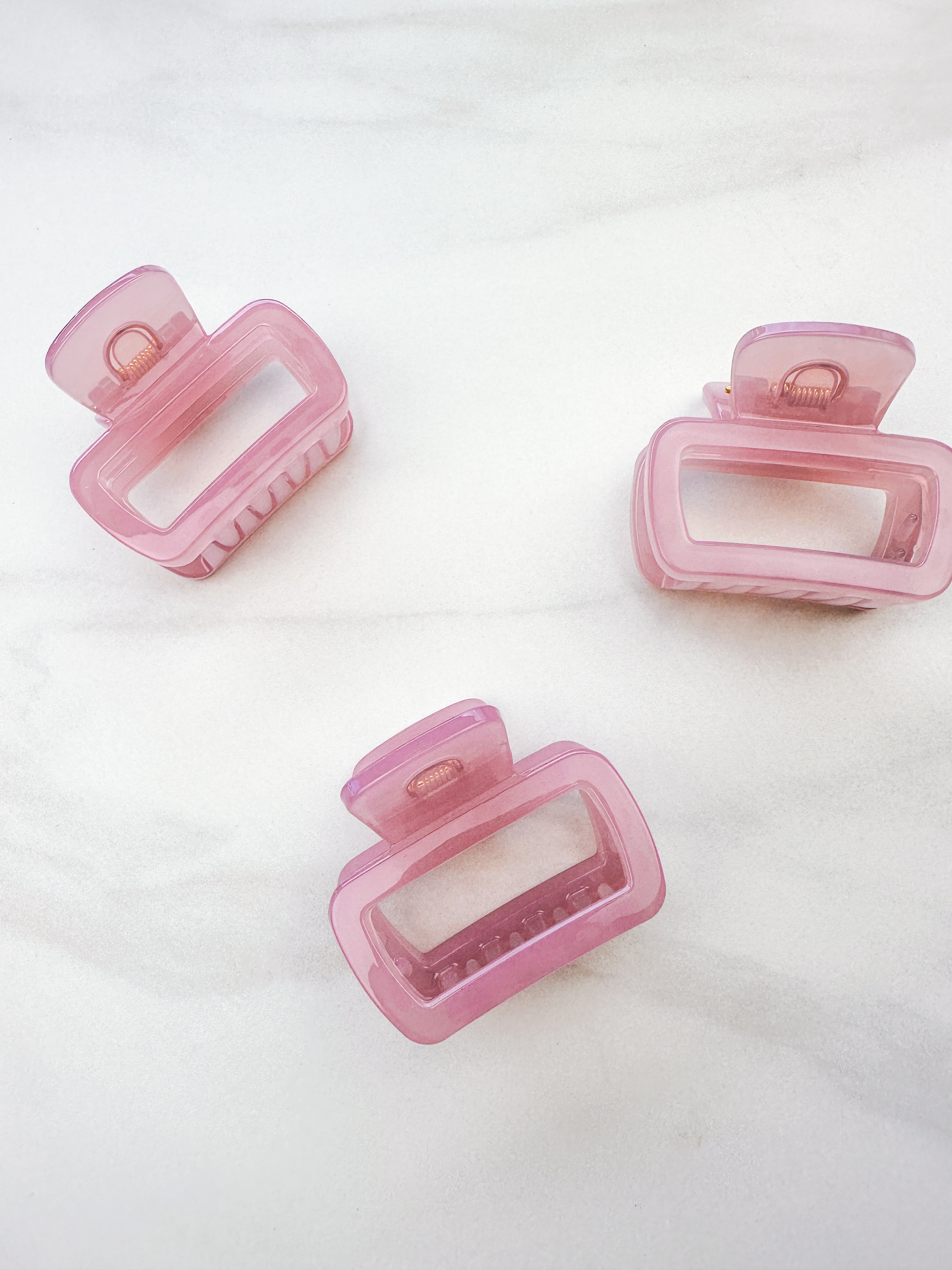 A close-up of a pink Happy Hour Lilac Clip, a glossy hair accessory with a hinge closure, perfect for all hair types. 1.8 inches long.