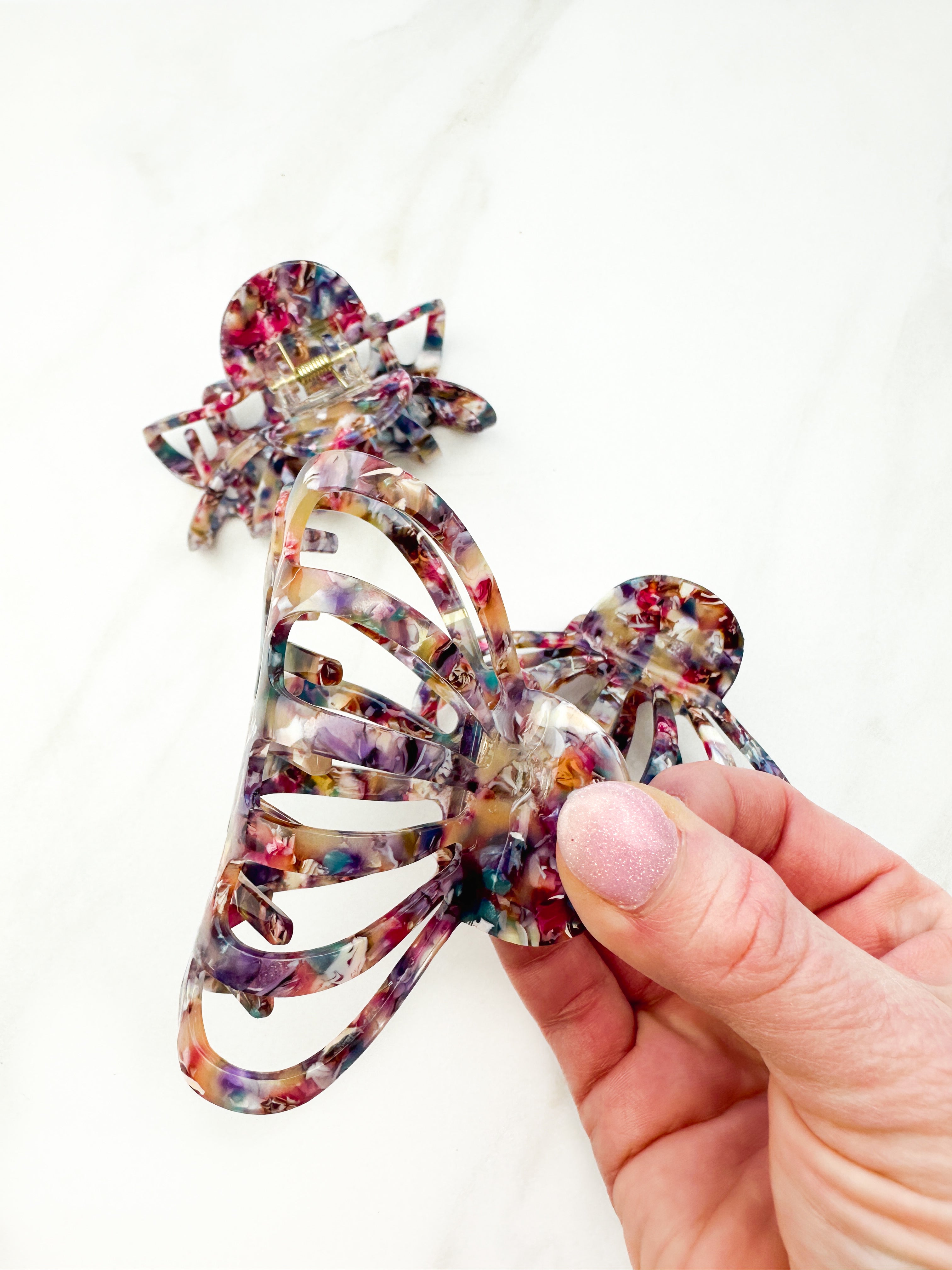 A group of Karma Lilac Clips, a fashionable hair accessory with a glossy rainbow material and a hinge closure. Perfect for all hair types and textures.