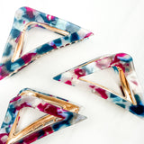 A Different Angle Lilac Clip, a group of blue, pink and white hair clips, perfect for all hair types and textures. 4.5 inches long with a glossy material and hinge closure. Hair-out-of-face approved.