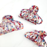 A group of Karma Lilac Clips, a fashionable hair accessory with a glossy rainbow material and a hinge closure. Perfect for all hair types and textures.