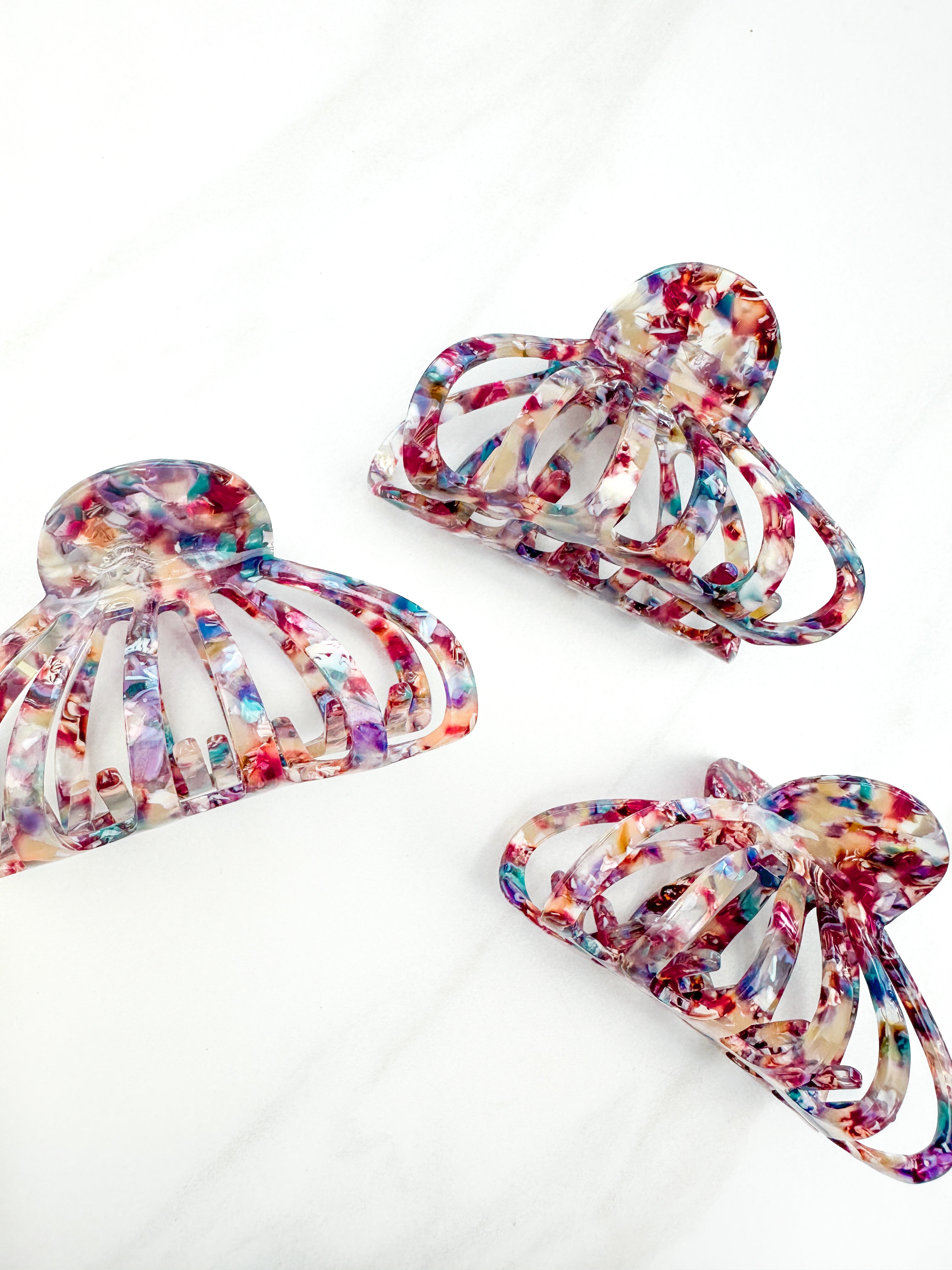 A group of Karma Lilac Clips, a fashionable hair accessory with a glossy rainbow material and a hinge closure. Perfect for all hair types and textures.