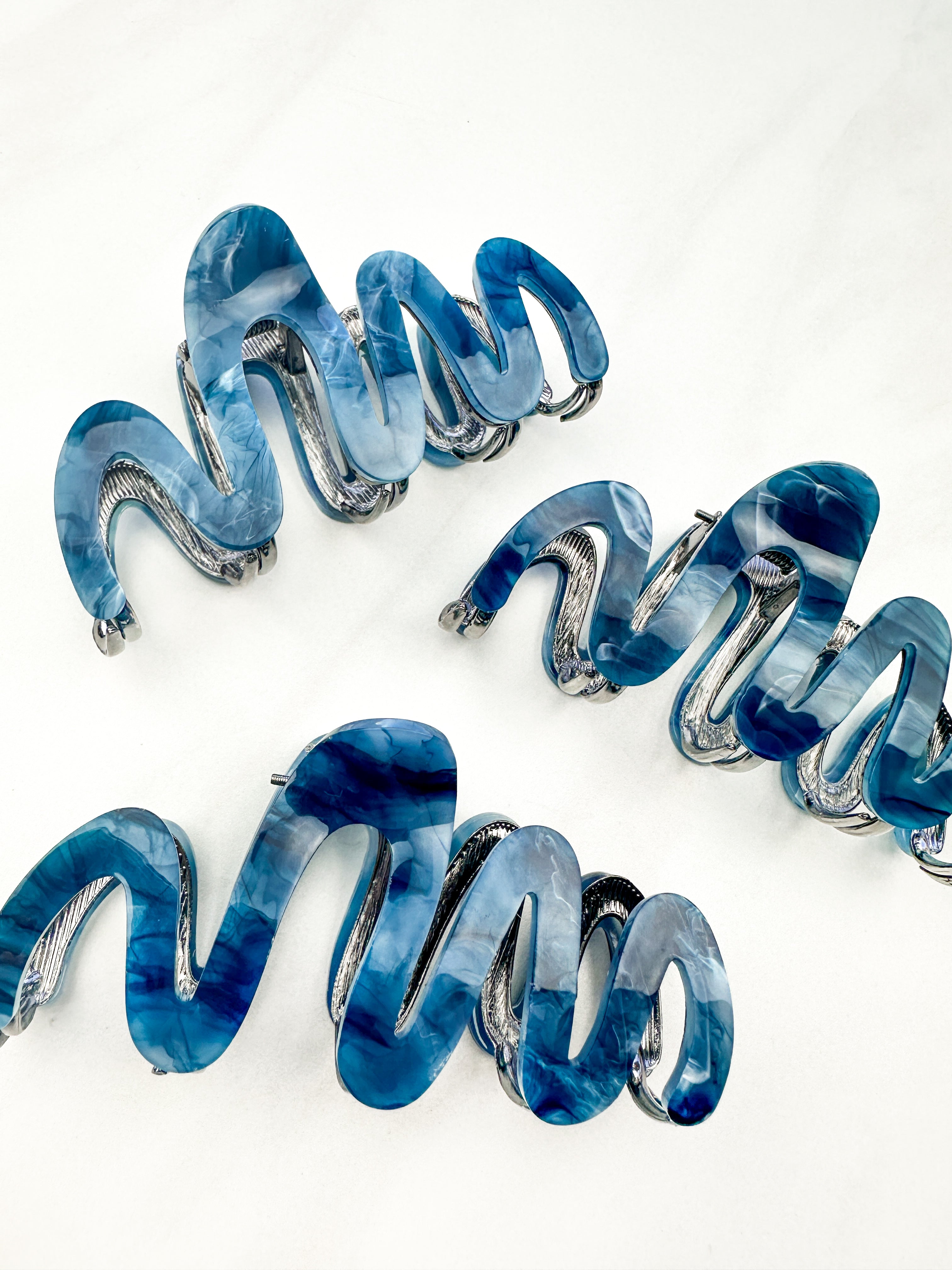 A group of zig zag-shaped dark blue marble hair clips with silver trim.