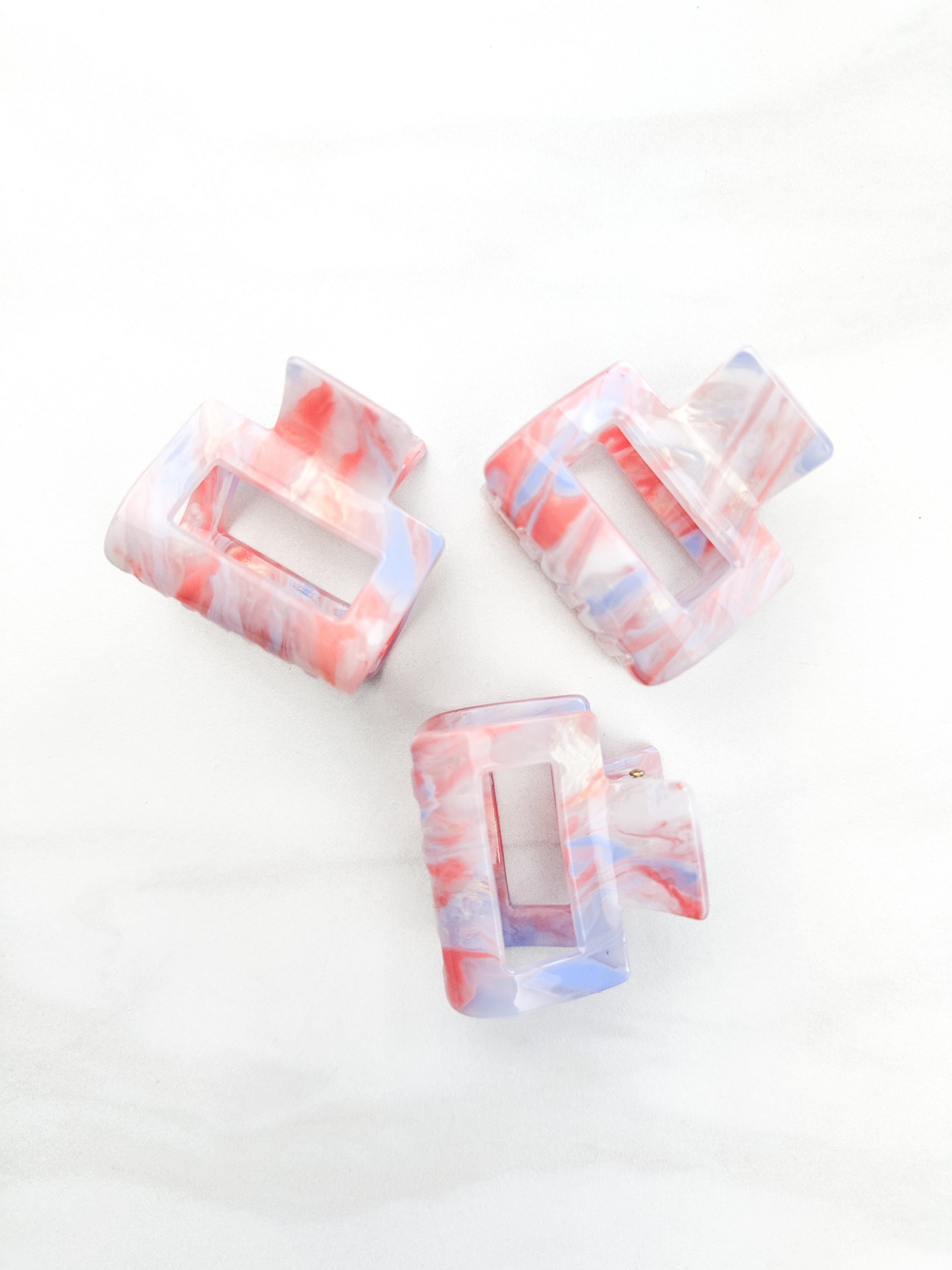 A group of plastic hair clips, including the Head in the Clouds Lilac Clip, on a white surface.