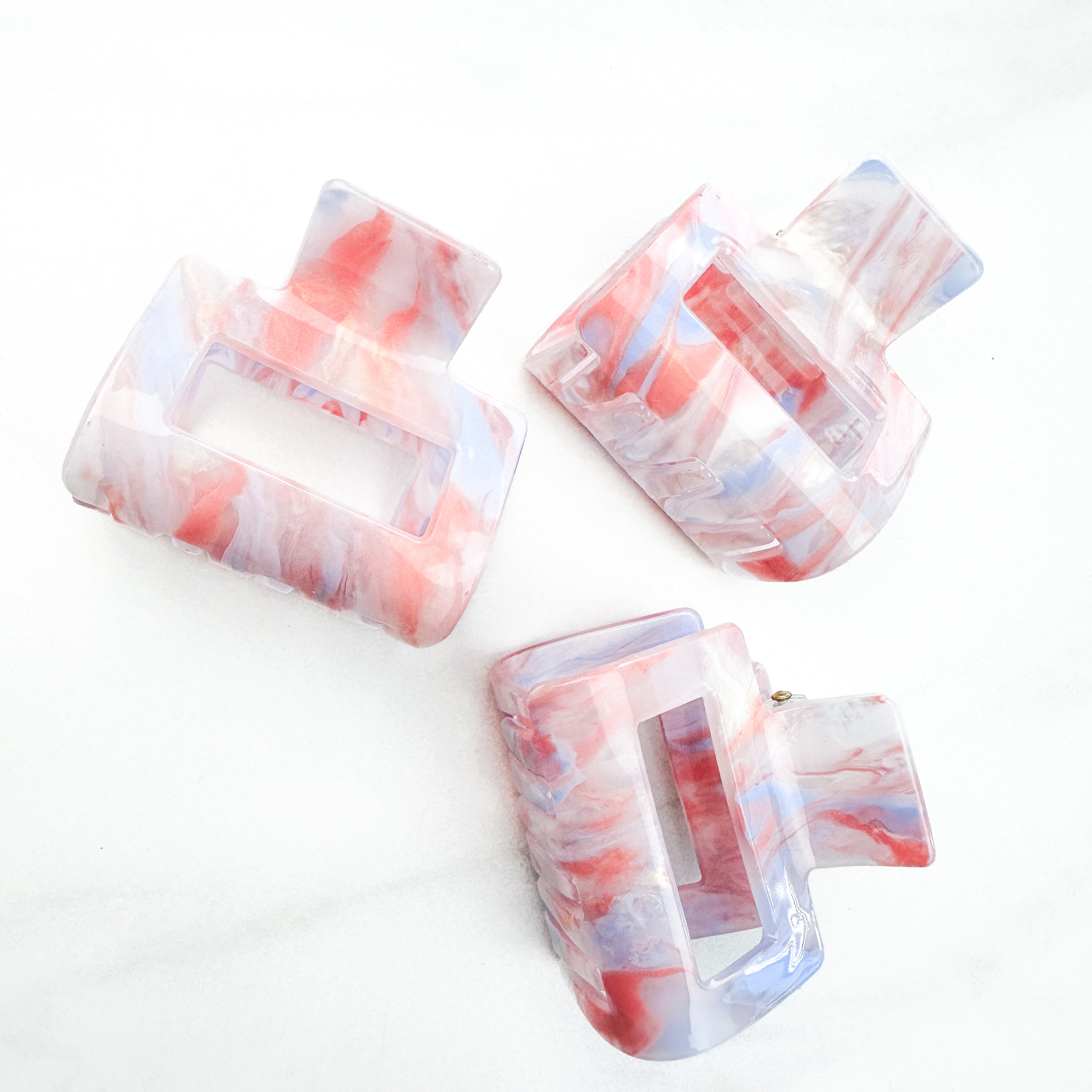 A group of plastic hair clips, including the Head in the Clouds Lilac Clip, on a white surface.