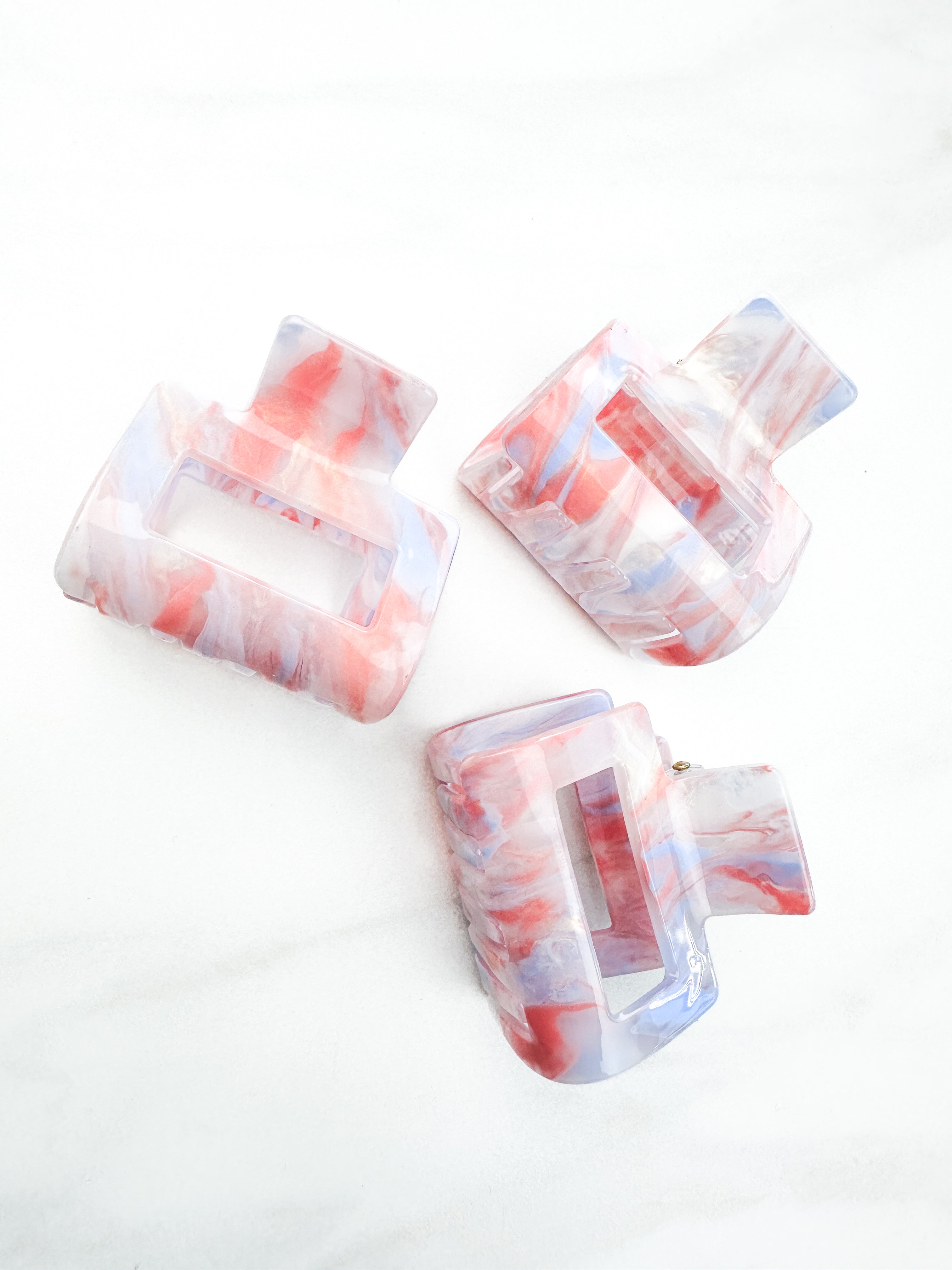 A group of plastic hair clips, including the Head in the Clouds Lilac Clip, on a white surface.