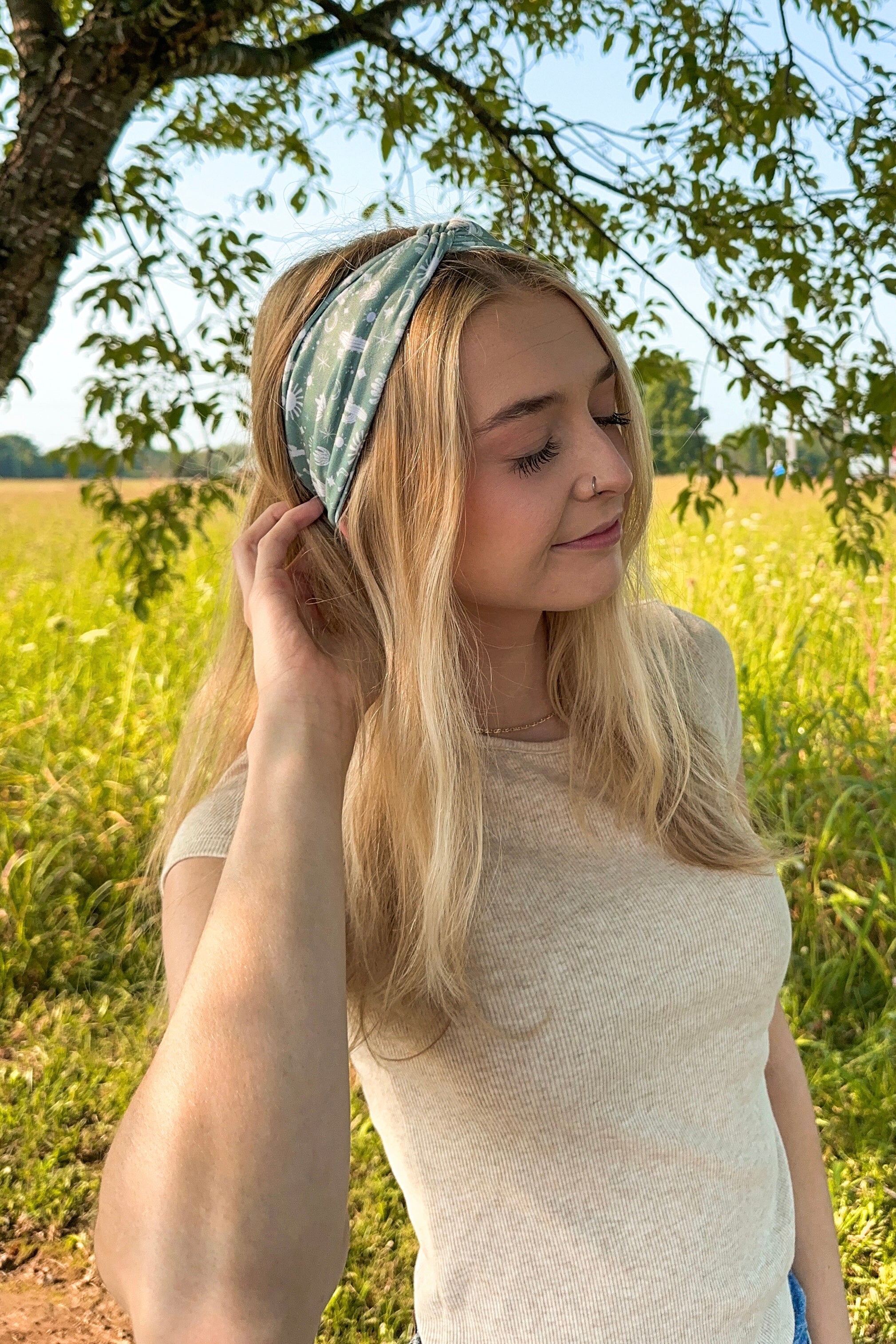 Woman in a field wearing a Keeping It Rural headband, showcasing its versatility and comfort for activities.