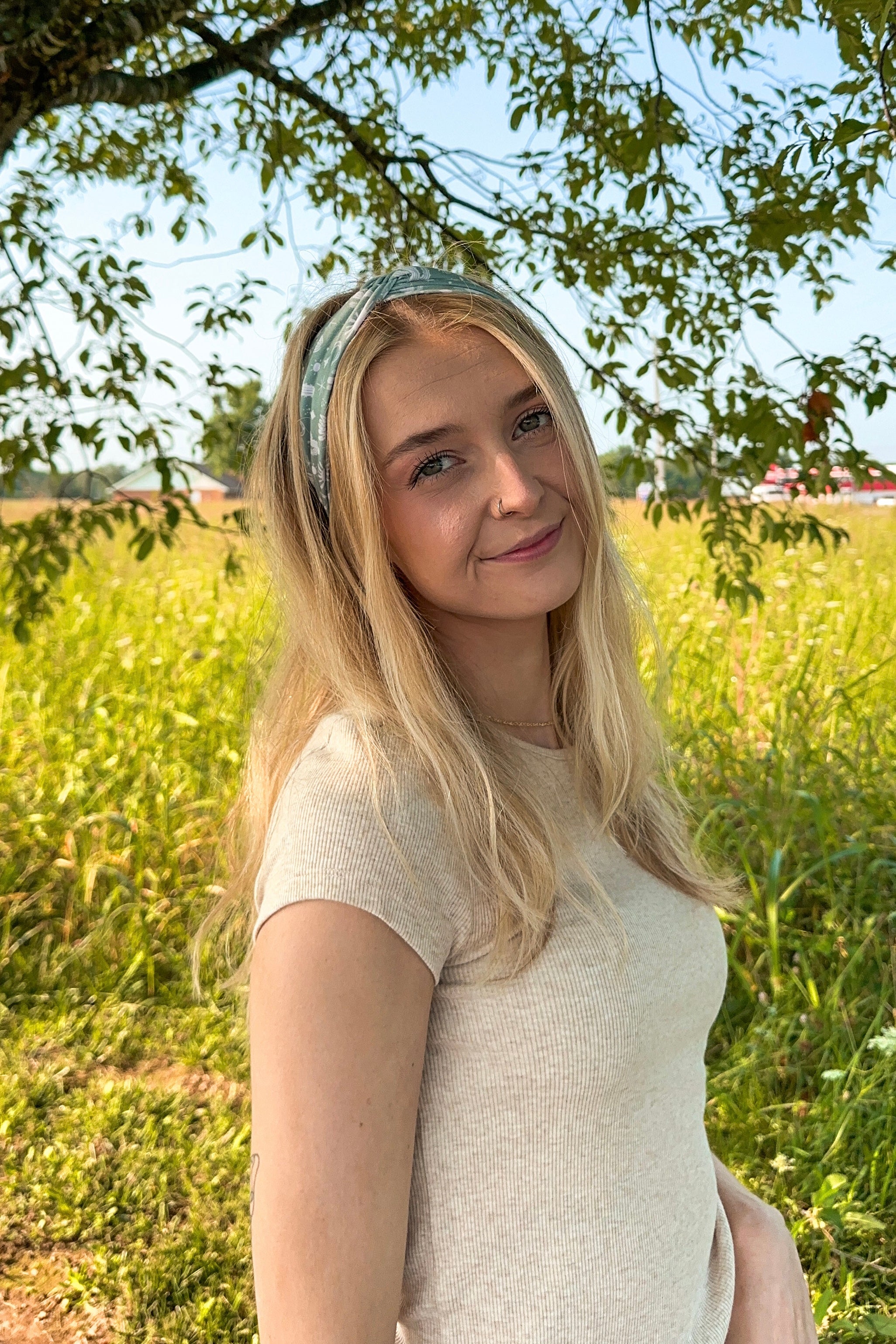 Woman in a field wearing a Keeping It Rural headband, showcasing its versatility and comfort for activities.