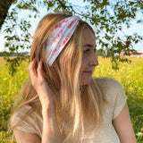 Woman smiling while wearing You Herd Me headband in a field, showcasing its versatile 3-in-1 twist style and buttery-soft, ultra-stretchy poly-knit blend.