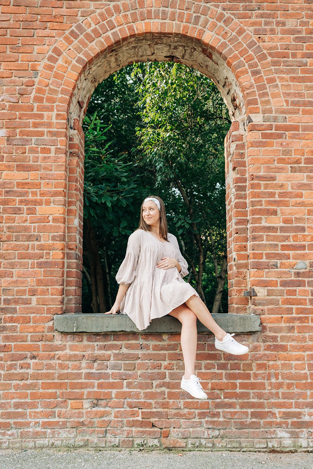 A woman smiling and confidently wearing the Springtime in Brooklyn headband from The Sarah Wallace Collection, showcasing its versatile twist style and non-slip design.