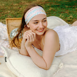 Woman smiling and confidently wearing the Emily Floral on Ivory headband, the perfect non-slip accessory for long shifts or play days.