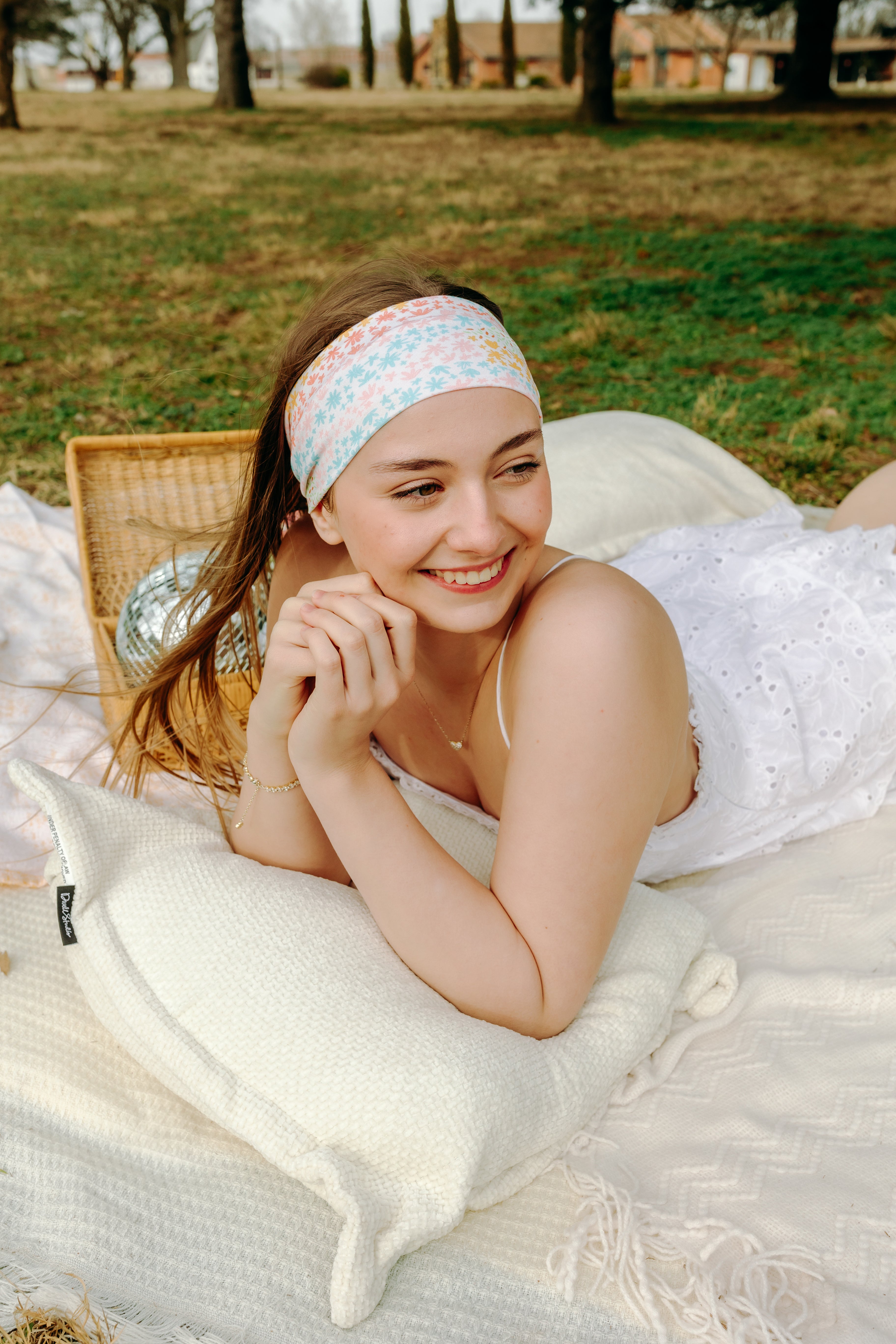 Woman smiling and confidently wearing the Emily Floral on Ivory headband, the perfect non-slip accessory for long shifts or play days.