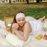 Woman smiling and confidently wearing the Emily Floral on Ivory headband, the perfect non-slip accessory for long shifts or play days.