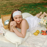 Woman smiling and confidently wearing the Emily Floral on Ivory headband, the perfect non-slip accessory for long shifts or play days.