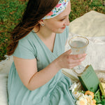 Woman smiling while wearing the Isabella Floral on Ivory headband, the perfect non-slip accessory for work or workouts.