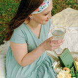 Woman smiling while wearing the Isabella Floral on Ivory headband, the perfect non-slip accessory for work or workouts.