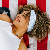 Woman with curly hair type happily wearing the most comfortable hand-made headband in the print Daisy Floral on Ivory. 