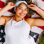 Woman with curly hair type happily wearing the most comfortable hand-made headband in the print Daisy Floral on Ivory. 