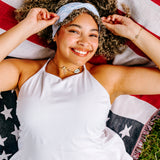 Woman with curly hair type happily wearing the most comfortable hand-made headband in the print Daisy Floral on Ivory. 