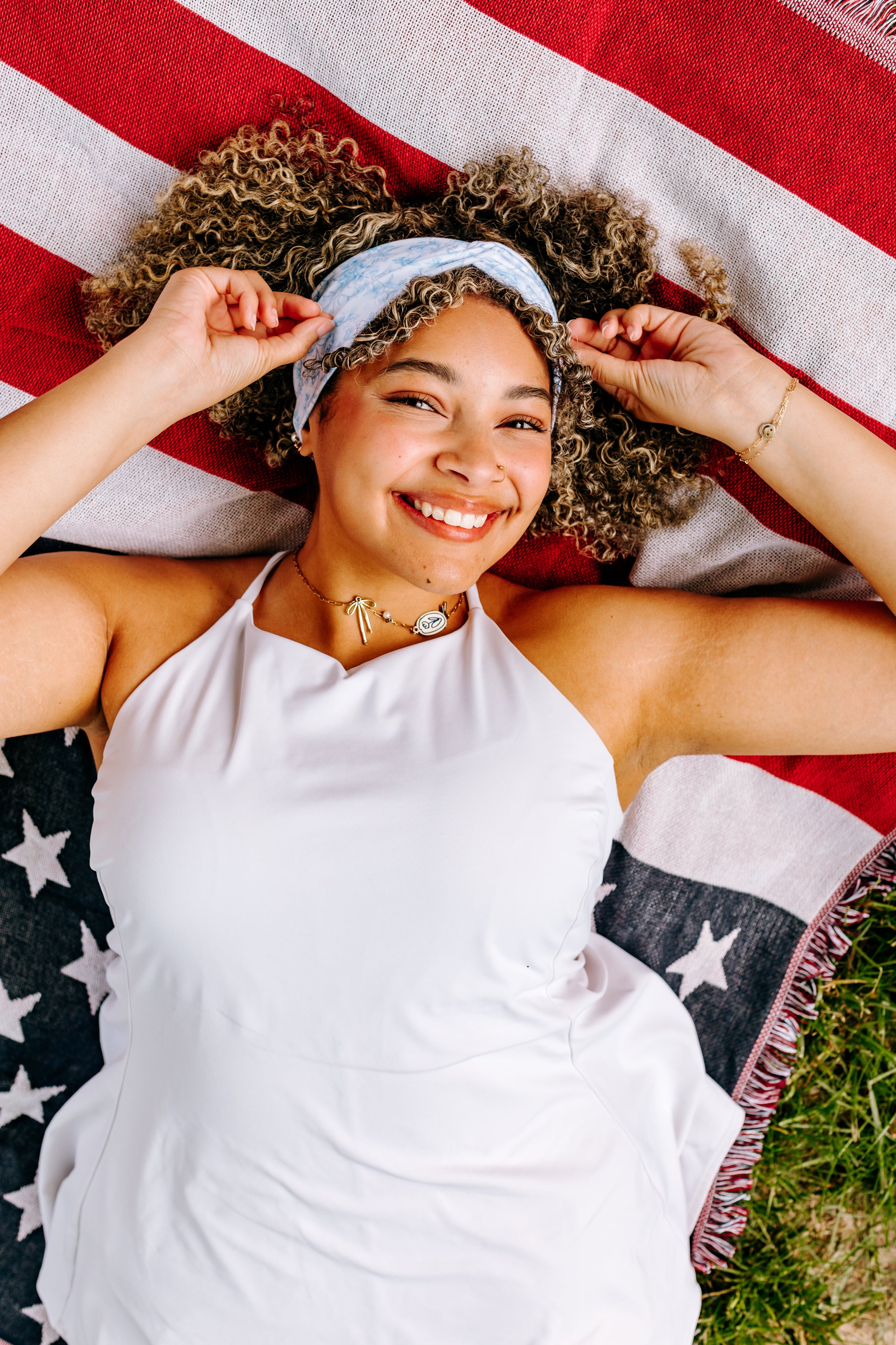 Woman with curly hair type happily wearing the most comfortable hand-made headband in the print Daisy Floral on Ivory. 