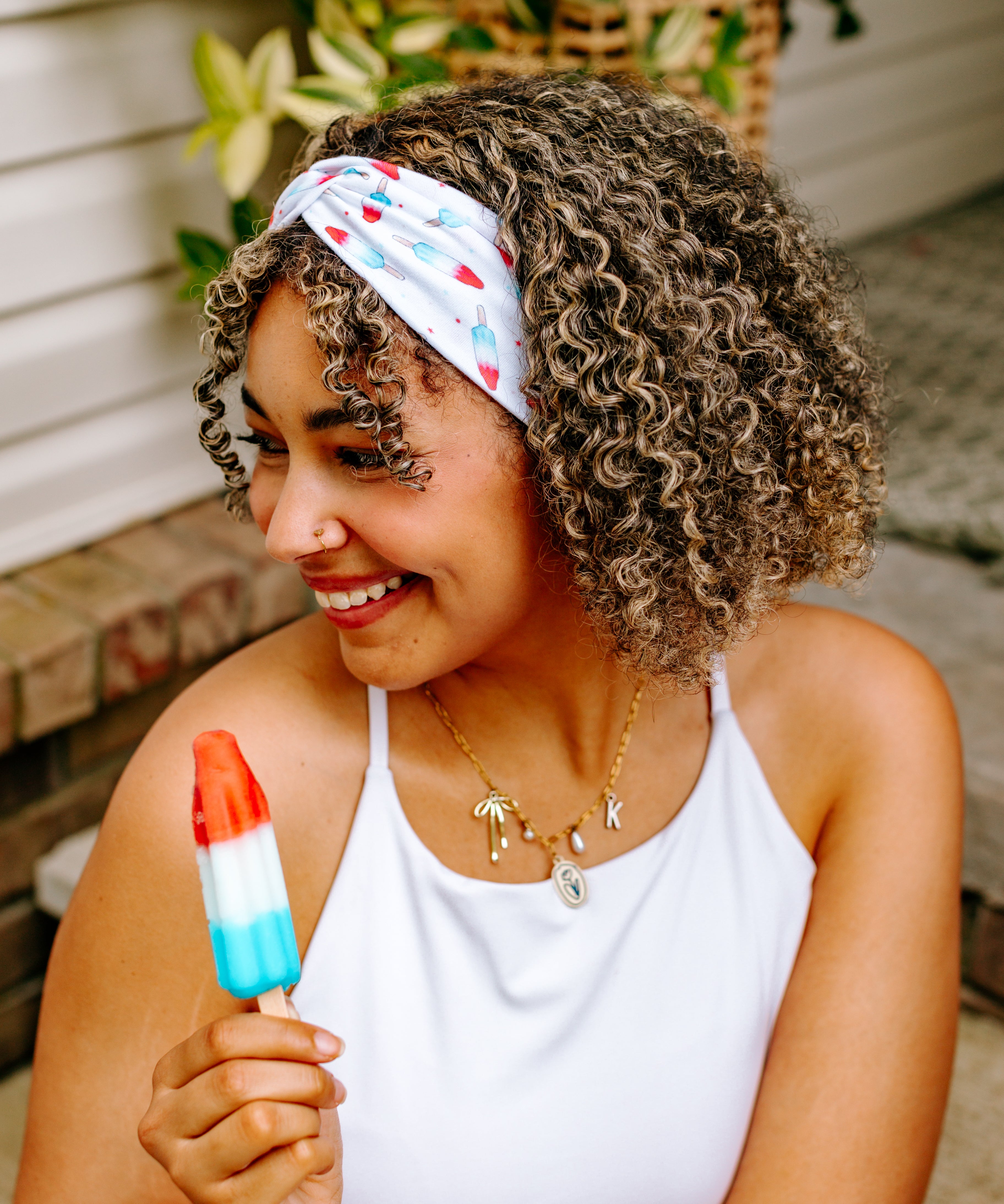 Woman with curly hair type happily wearing the most comfortable hand-made headband in the print Stay Cool. 