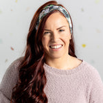 A black headband with white floral pattern and "Mama" script, offering confidence and functionality. Features one size fits most, machine washable, ultra stretchy poly-knit blend, versatile 3-in-1 twist style, sweat absorbent double-layer fabric.