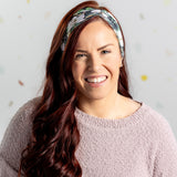 A black headband with white floral pattern and "Mama" script, offering confidence and functionality. Features one size fits most, machine washable, ultra stretchy poly-knit blend, versatile 3-in-1 twist style, sweat absorbent double-layer fabric.