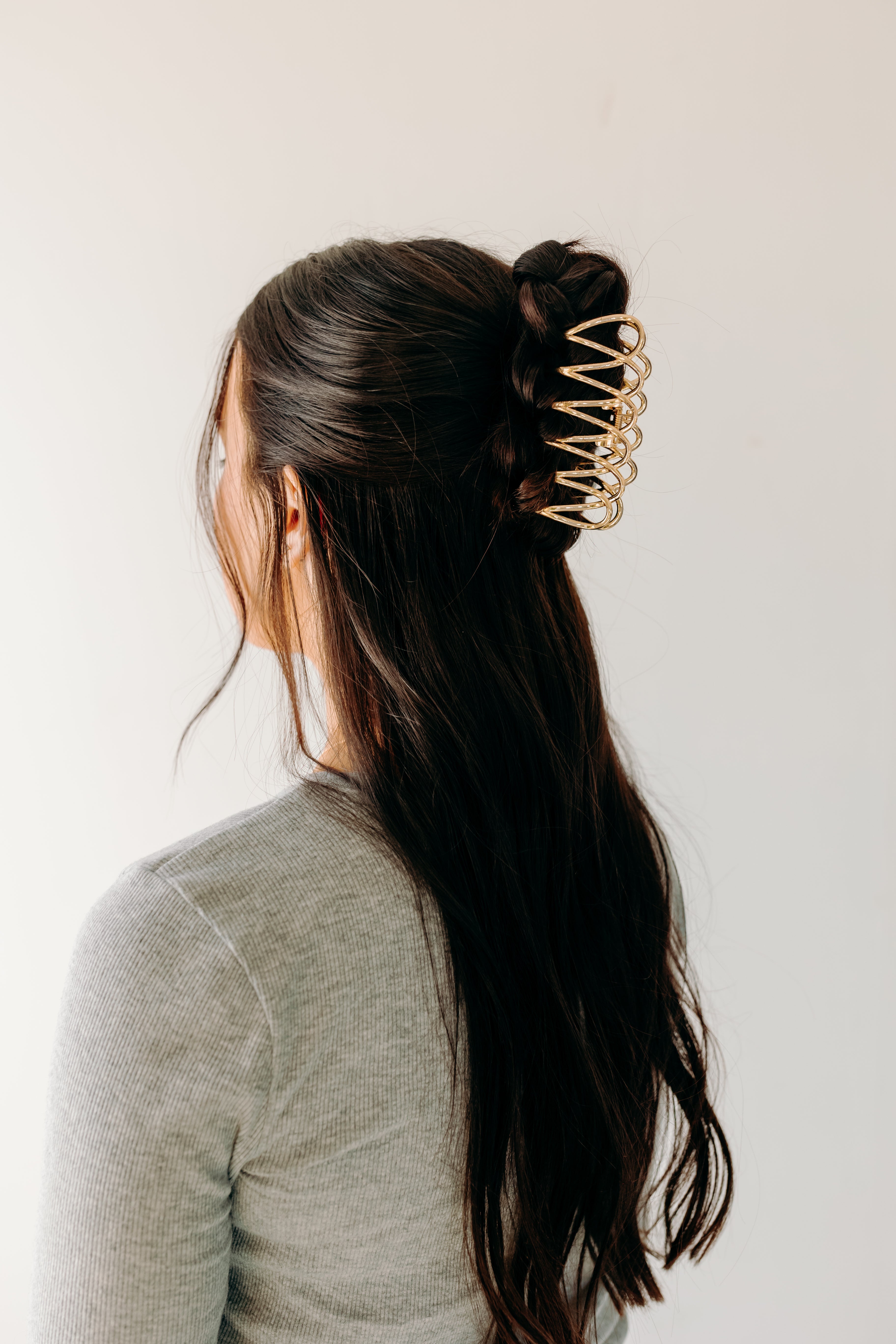 A woman wearing a gold Out Of Office Lilac clip, showcasing the half-up hairstyle. 3.6 inches long, shiny gold metal, perfect for all hair types. Hinge closure for a secure fit.