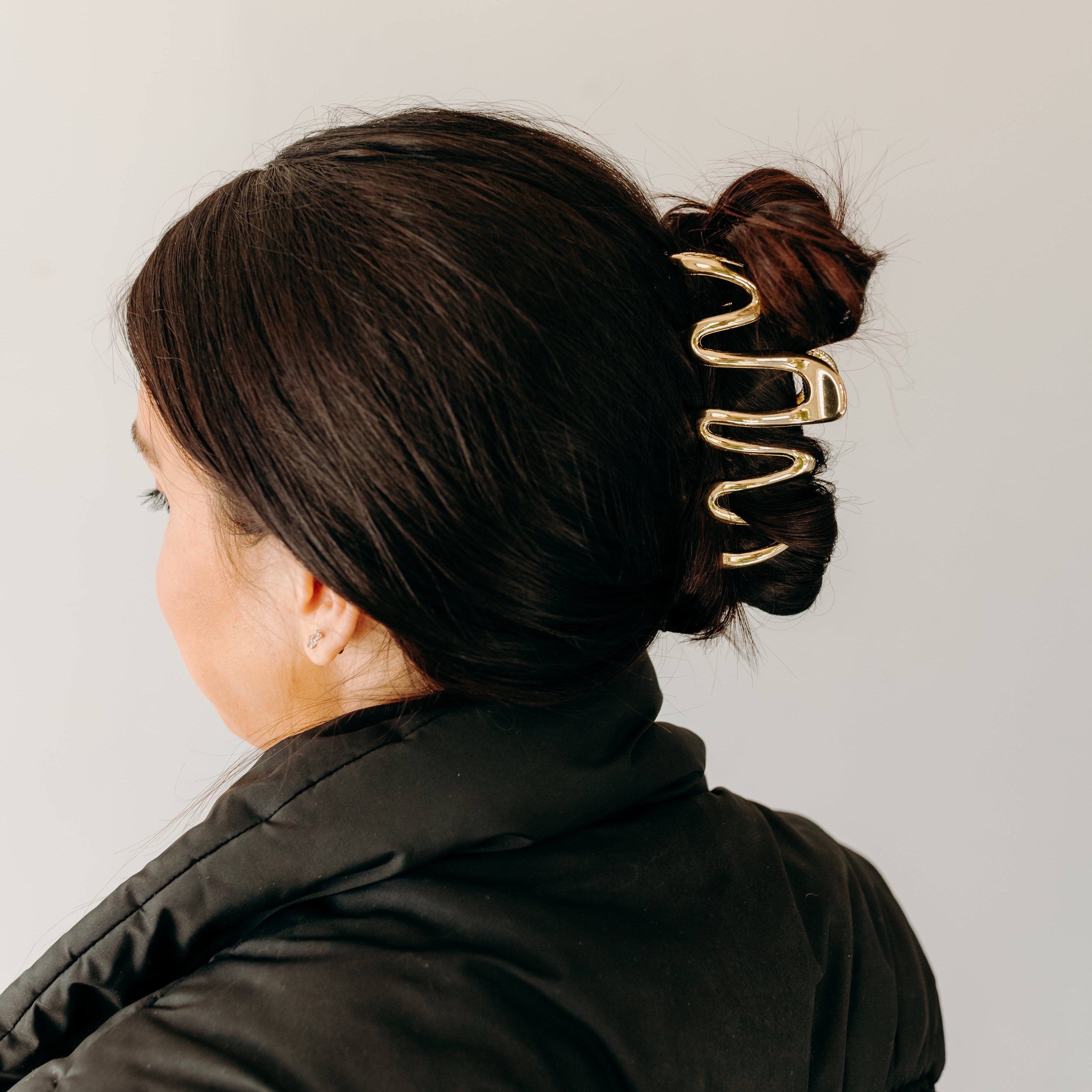 Woman wearing a gold Comes in Waves Lilac Clip hair clip, showcasing her hairstyle.