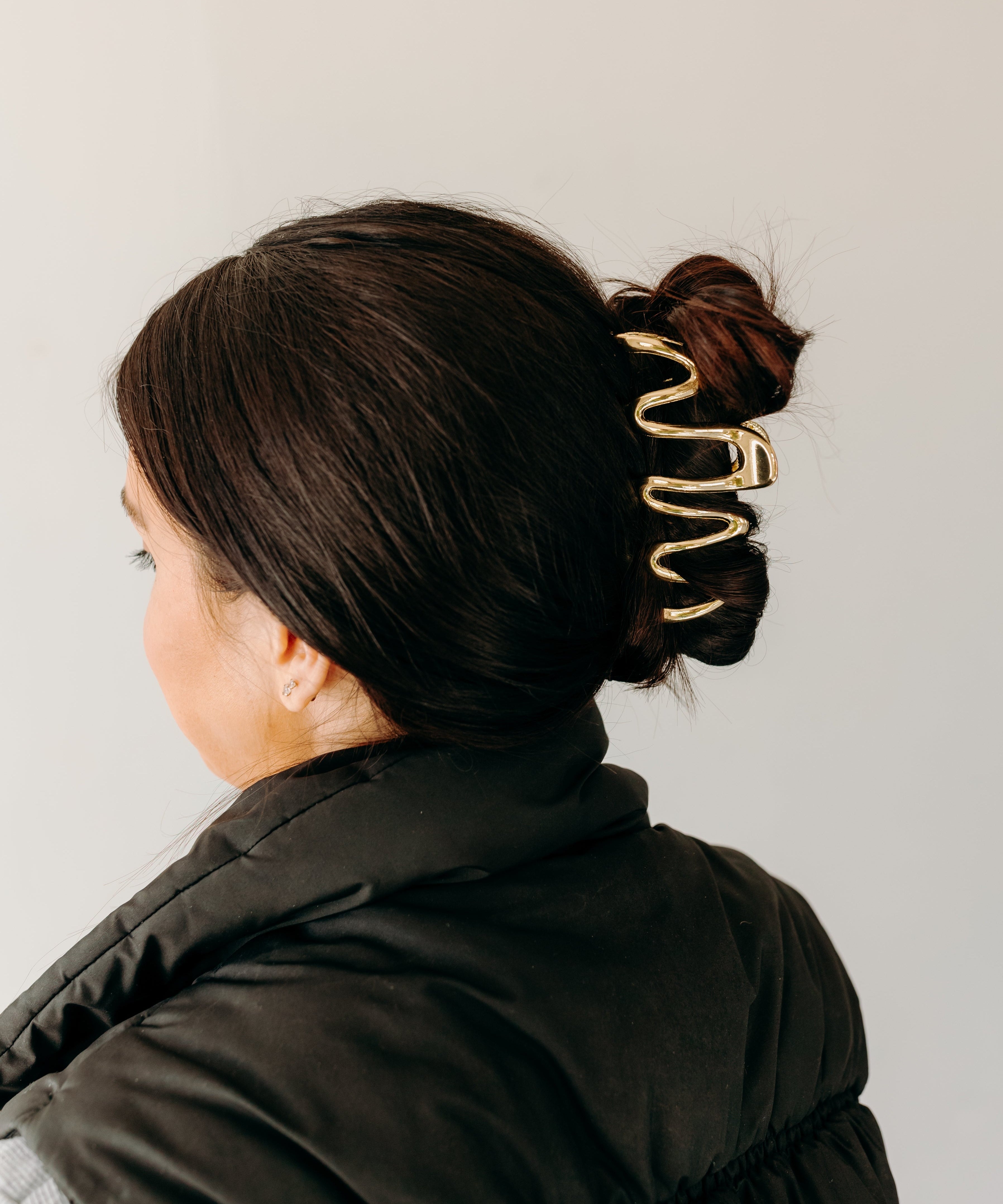 Woman wearing a gold Comes in Waves Lilac Clip hair clip, showcasing her hairstyle.