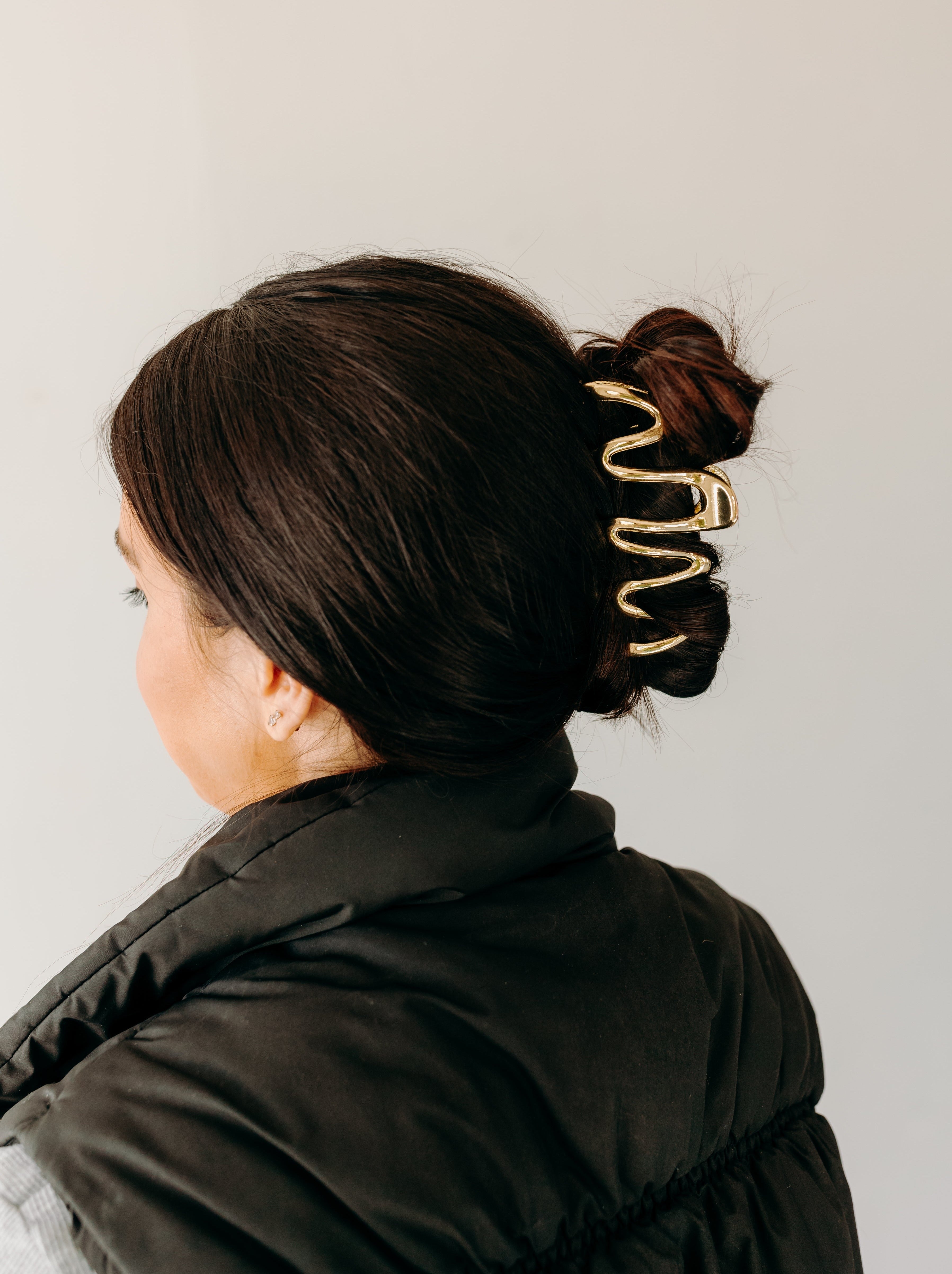 Woman wearing a gold Comes in Waves Lilac Clip hair clip, showcasing her hairstyle.