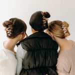 A group of women wearing various Comes in Waves Lilac Clip hair clips, showcasing their hairstyles.