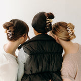 A group of women wearing various Comes in Waves Lilac Clip hair clips, showcasing their hairstyles.