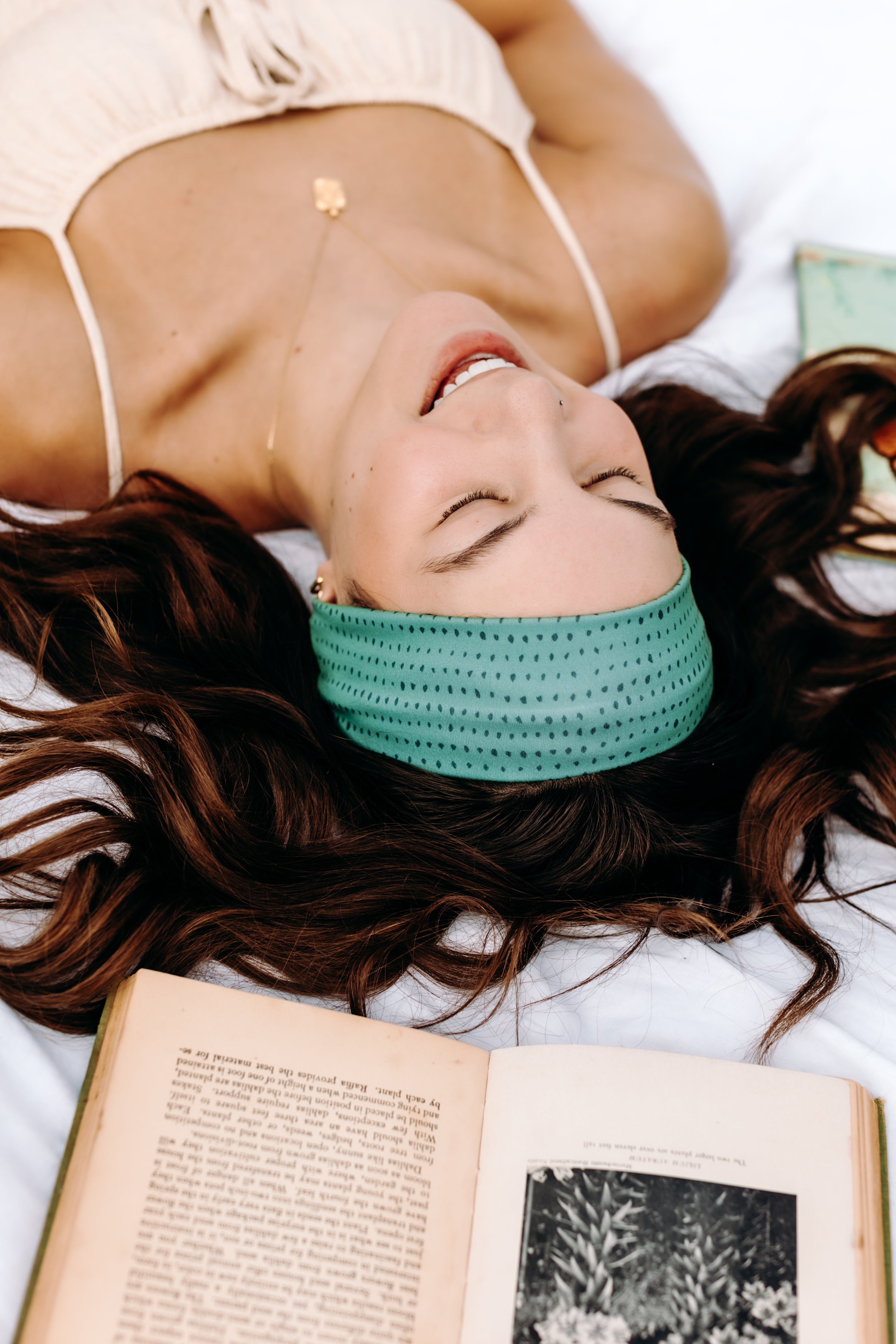 Woman with long hair happily wearing the most comfortable hand-made headband in the print Dottie on Emerald.