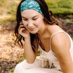 Woman with long hair happily wearing the most comfortable hand-made headband in the print Arwen Floral.