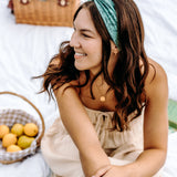 Woman with long hair happily wearing the most comfortable hand-made headband in the print Opal Floral.